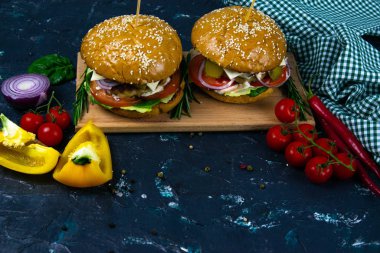 İki ev yapımı mantarlı sığır burger, mikro yeşiller, ahşap kesim tahtasındaki kırmızı soğan.