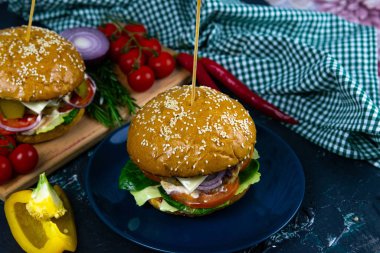 İki ev yapımı mantarlı sığır burger, mikro yeşiller, ahşap kesim tahtasındaki kırmızı soğan.