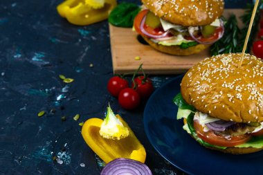 İki ev yapımı mantarlı sığır burger, mikro yeşiller, ahşap kesim tahtasındaki kırmızı soğan.