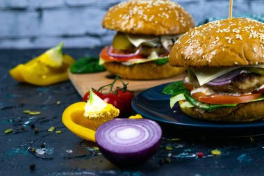 İki ev yapımı mantarlı sığır burger, mikro yeşiller, ahşap kesim tahtasındaki kırmızı soğan.