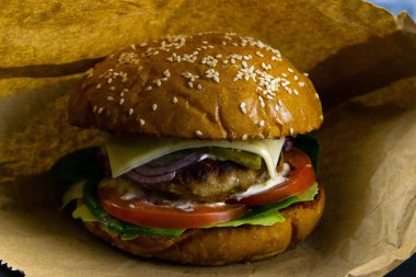 Hamburgers on white wrappers. Old wooden table with burgers. Juicy lettuce and warm buns.