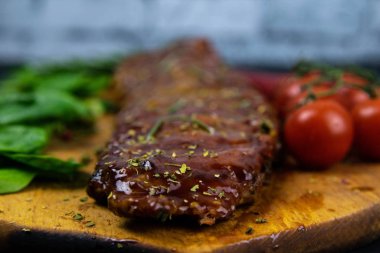 Barbecue Pork Spare Ribs close-up with tomatoes and basil as top view on an old cutting board