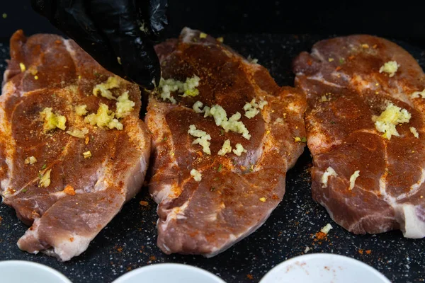 Vepřové steaky ochucené červeným pepřem, kořením a často. Čerstvé syrové vepřové panenky na dřevěné řezací desce. — Stock fotografie