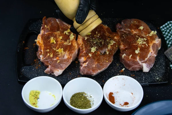 A chef in black gloves sprinkled with pepper from hand pepper a raw tenderloin. — 스톡 사진