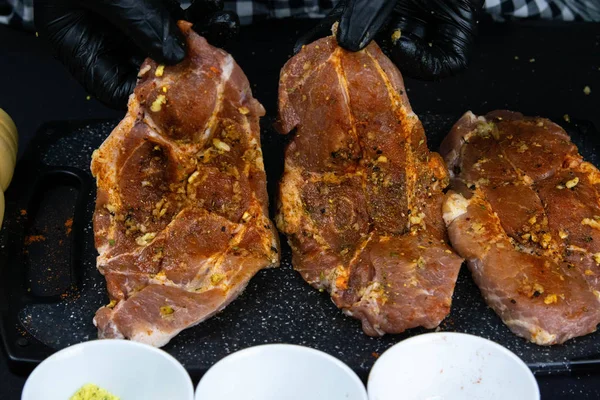 A chef in black gloves prepares a raw tenderloin. Fresh raw pork tenderloin on a wooden cutting board. — 스톡 사진