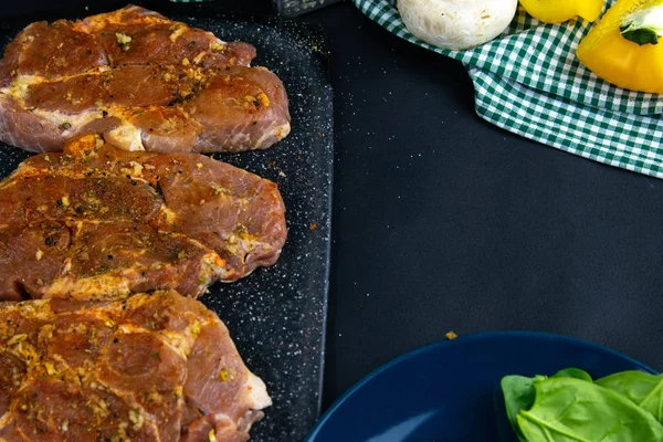 Three slices of raw steak and next to a plate of avocado and pour basil — 스톡 사진