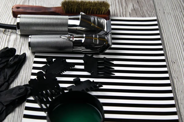 Máquinas de corte de pelo, boquillas de diferentes tamaños, peines y geles para peinar, dispuestas sobre una hermosa franja blanca negra — Foto de Stock