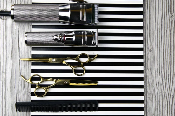 Máquinas de corte de pelo, boquillas de diferentes tamaños, peines y geles para peinar, dispuestas sobre una hermosa franja blanca negra — Foto de Stock