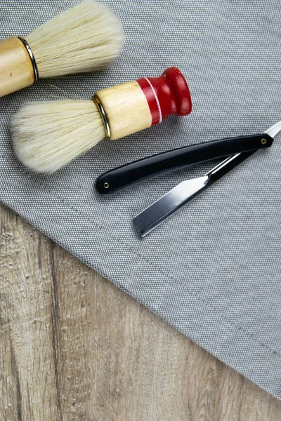 Kit de afeitado, concepto de peluquero, cepillos de espuma y maquinilla de afeitar peligrosa se presentan en una toalla a rayas — Foto de Stock