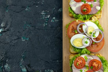 Tahtada jambonlu ve domatesli üç sandviç..