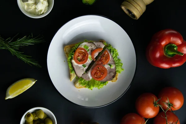 Deliciosos sándwiches cortados por la mitad con lechuga y jamón en plato blanco de cerca . — Foto de Stock