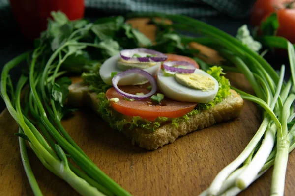 Delicious sandwiches with with tomato egg and lettuce on wooden board close-up.