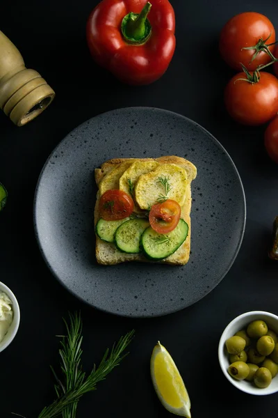 Patatesli lezzetli sandviçler, salatalık ve domatesler yakın plan gri tabakta..