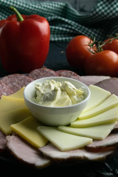 Plato gris con souce alrededor del salami, jamón, queso y mozzarella. Tomate, souce, aceitunas, limón, aceite de oliva con especias — Foto de Stock