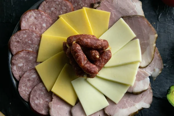 Plato gris con salchichas alrededor del salami, jamón, queso y mozzarella. Tomate, souce, aceitunas, limón, aceite de oliva con especias — Foto de Stock