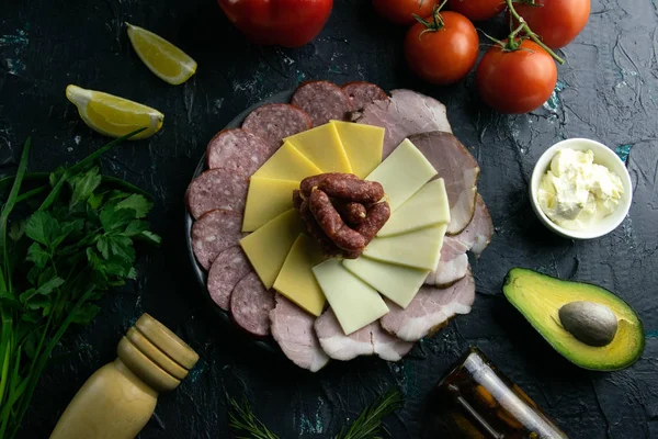 Plato gris con salchichas alrededor del salami, jamón, queso y mozzarella. Tomate, souce, aceitunas, limón, aceite de oliva con especias — Foto de Stock