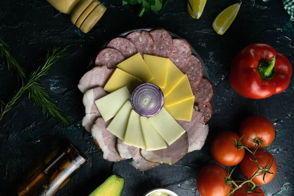 Plato gris con cebolla alrededor del salami, jamón, queso y mozzarella. Tomate, souce, aceitunas, limón, aceite de oliva con especias — Foto de Stock