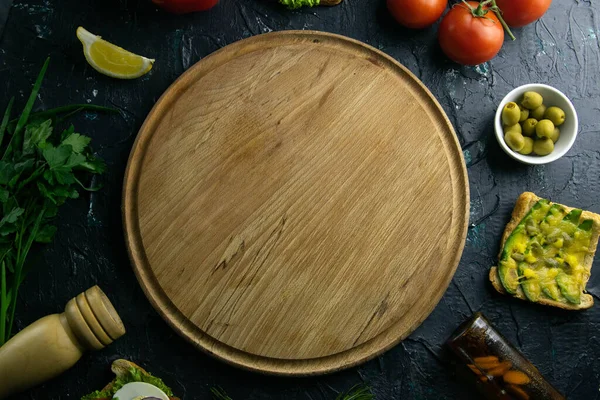 Placa de madeira com espaço livre. Em torno de tomate, souce, azeitonas, limão, azeite com especiarias e sanduíches — Fotografia de Stock