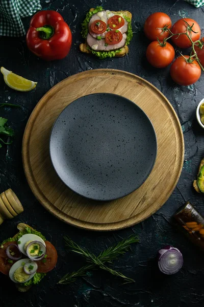 Placa cinzenta com espaço livre na placa de madeira. Em torno de tomate, souce, azeitonas, limão, azeite com especiarias e sanduíches — Fotografia de Stock