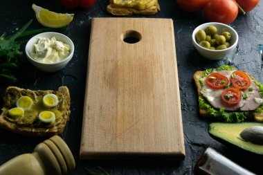 Temiz uzayı olan tahta tahta bir tahta. Domates, sos, zeytin, limon, zeytinyağı ve baharatlı sandviç.