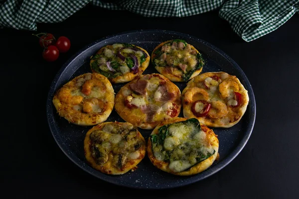 Em uma pizza de bandeja: com camarão, com cogumelos, com espinafre e cebolas, com bacon, com paperoni, com tomates — Fotografia de Stock