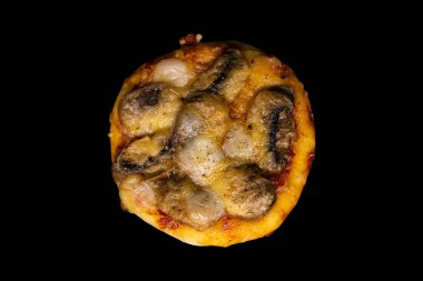Siyah arka planda mantarlı ve peynirli küçük bir pizza.