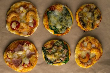 Küçük mini pizza. Farklı mini pizzalar. Kağıt üzerinde pizza: karidesli, mantarlı, ıspanaklı, soğanlı, pastırmalı, kağıtlı, domatesli.