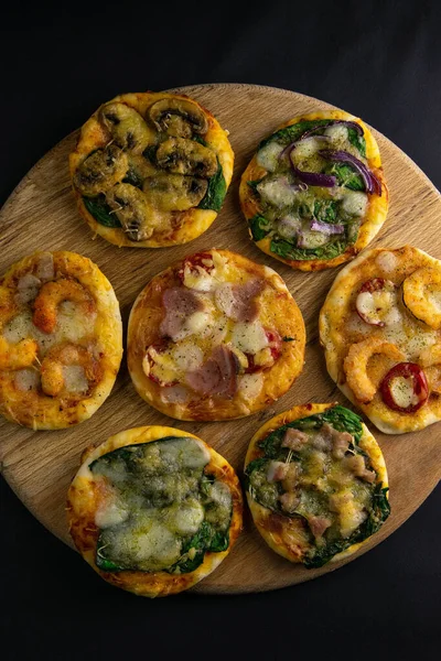 Küçük mini pizza. Farklı mini pizzalar. Tahta üzerinde pizza: karidesli, mantarlı, ıspanaklı, soğanlı, pastırmalı, kağıtlı, domatesli — Stok fotoğraf