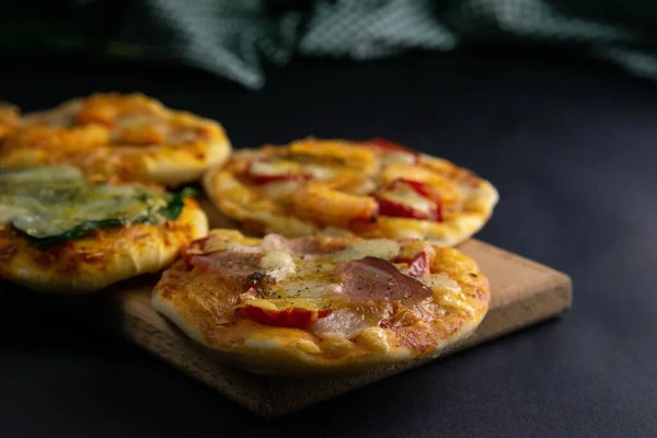 Kleine Mini-Pizza. Set mit verschiedenen Mini-Pizzen. Pizza auf Holzbrett: mit Garnelen, mit Pilzen, mit Spinat und Zwiebeln, mit Speck, mit Paperoni, mit Tomaten — Stockfoto