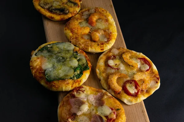 Küçük mini pizza. Farklı mini pizzalar. Tahta üzerinde pizza: karidesli, mantarlı, ıspanaklı, soğanlı, pastırmalı, kağıtlı, domatesli — Stok fotoğraf