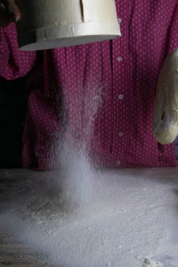 Un dolu, kadınların elleri masayı un serpiyor. Hamur ve pişirme için hazırlanıyor