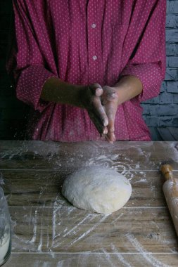 Bir kadın un damlalarının etrafına ellerini çırpıyor. Ekmek pişirmek için hamur hazırlama süreci