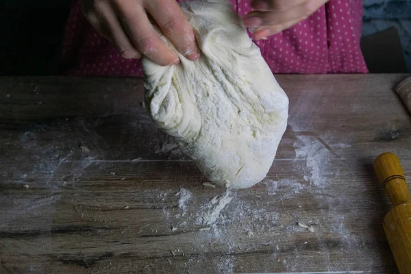 Kvinders hænder bland dejen på et træbord. Klargøring af brød til bagning - Stock-foto