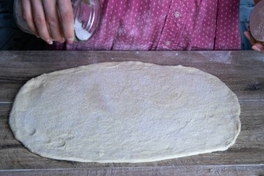 Kadının eli hamura şeker serper, elmalı dürüm hazırlamak için.