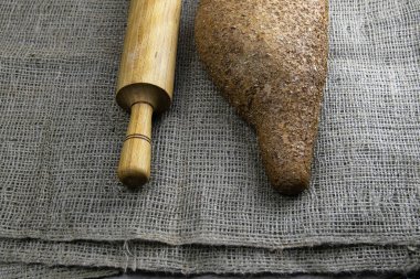 Hamur için merdaneli bir somun ekmek keten bir çantanın üzerinde duruyor..