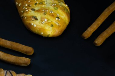 Siyah kırsal arka planda tahıllı farklı taze ekmek türleri. Ekmek üst konumda duruyor.