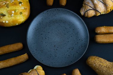 Siyah kırsal arka planda tahıllı farklı taze ekmek türleri. Ekmek gri tabağın etrafında duruyor.