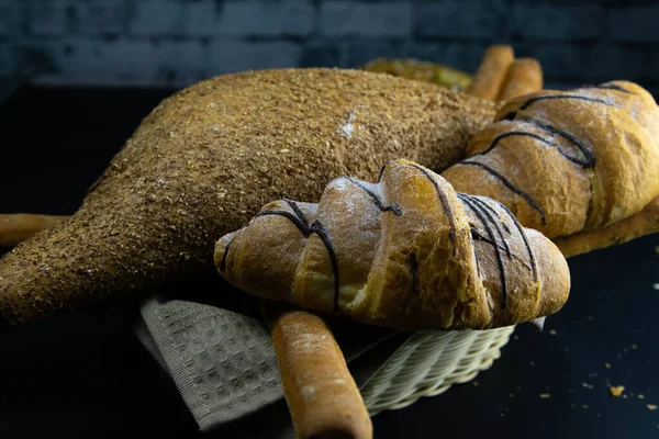 Różne rodzaje świeżego chleba z ziarnem na czarnym rustykalnym tle. — Zdjęcie stockowe