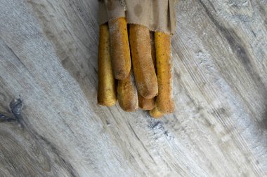 Tahta bir masanın üzerinde duran el işi çantasındaki farklı baharatlı ekmek çubukları..