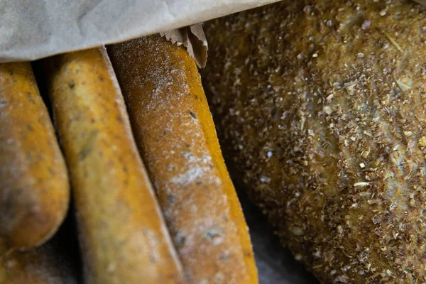 Diversi tipi di pane fresco in una borsa artigianale poggiano su un tavolo di legno . — Foto Stock