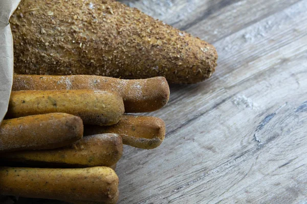 Различные виды свежего хлеба в ремесленной сумке стоят на деревянном столе . — стоковое фото