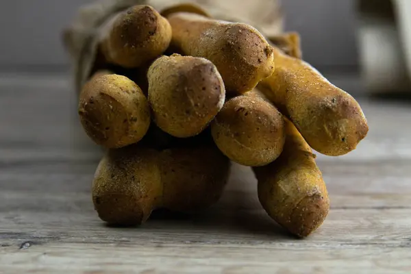 Diversi tipi di bastoncini di pane speziato fresco in una borsa artigianale poggiano su un tavolo di legno . — Foto Stock