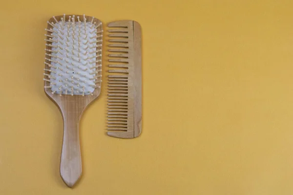 Cosméticos para el cuidado del cabello con jojoba, argán o aceite de coco. Botellas y peines de aceite sobre fondo naranja . —  Fotos de Stock