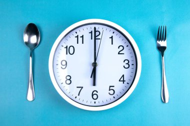 Çatal ve kaşığın yanında tam olarak 6 saat gösteren bir saat mavi bir arka plandadır..