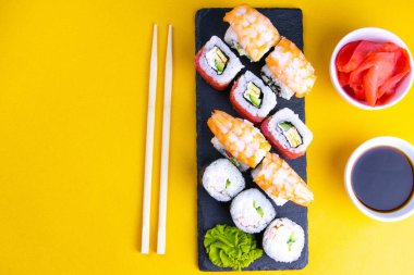 Suşi için granit tahta, suşi için çubuk, kırmızı marinaginger ve soya sosu yanında her çeşit rulo var..
