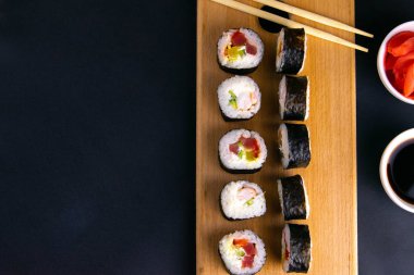 Suşi için granit tahta, suşi için çubuk, kırmızı marinaginger ve soya sosu yanında her çeşit rulo var..