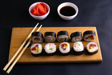 Suşi için granit tahta, suşi için çubuk, kırmızı marinaginger ve soya sosu yanında her çeşit rulo var..