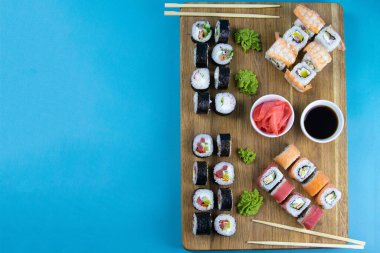 Maki ve Uramaki 'li lezzetli Nigiri suşisi ve Tempura dürümleriyle ahşap tabağın en üst görüntüsü.