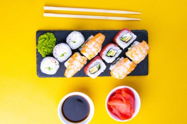 Suşi için granit tahta, suşi için çubuk, kırmızı marinaginger ve soya sosu yanında her çeşit rulo var..