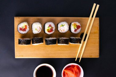 Suşi için granit tahta, suşi için çubuk, kırmızı marinaginger ve soya sosu yanında her çeşit rulo var..